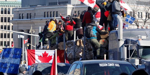 ZDJĘCIE PLIKU: Demonstranci stoją na przyczepie przewożącej kłody, podczas gdy kierowcy ciężarówek i kibice uczestniczą w konwoju protestującym przeciwko mandatom szczepionki na koronawirusa (COVID-19) dla kierowców ciężarówek transgranicznych w Ottawie, Ontario, Kanada, 29 stycznia 2022 r. REUTERS/PATRICK DOYLE/PLIK Obraz