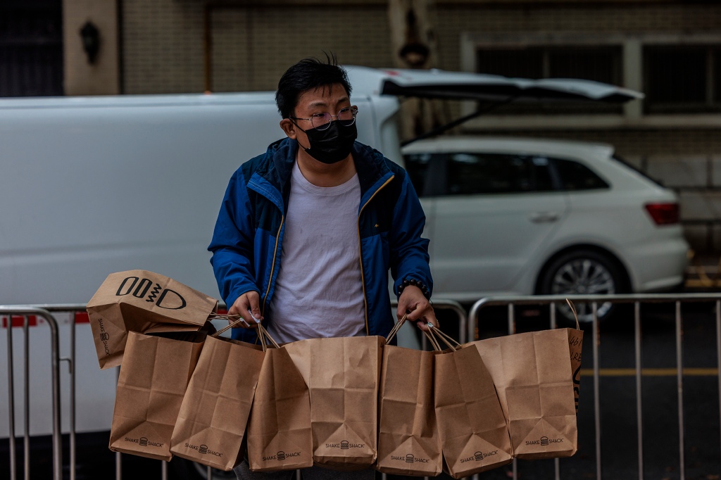 Dostawca dostarcza jedzenie do zamkniętej wspólnoty mieszkaniowej w Szanghaju w Chinach, 23 kwietnia 2022 r.