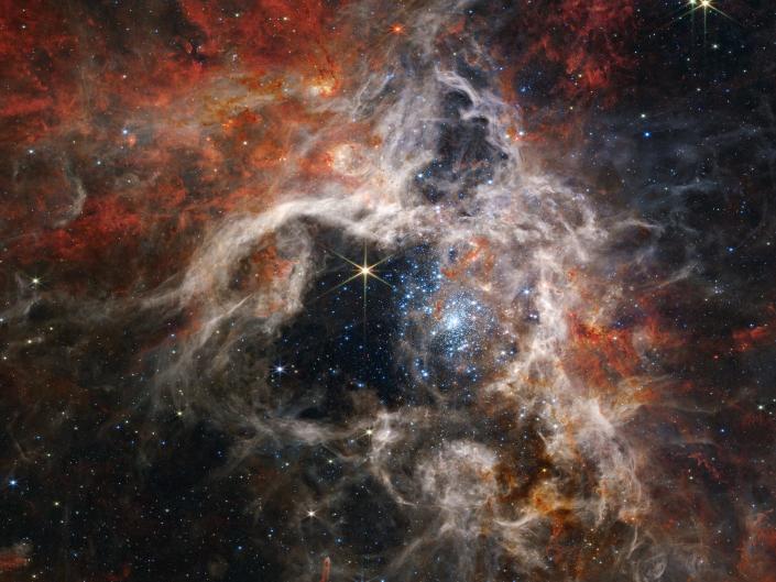 Mgławica Tarantula kosmiczna chmura pyłu pomarańczowo-biała siatka z gwiazdami
